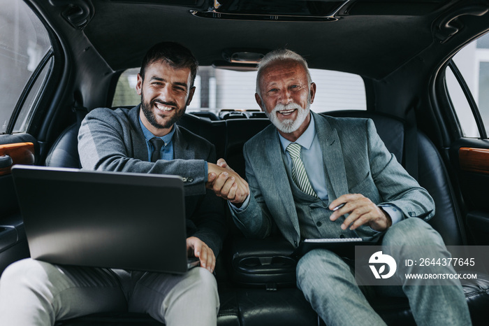 Senior businessman and his assistant sitting in limousine and working together.