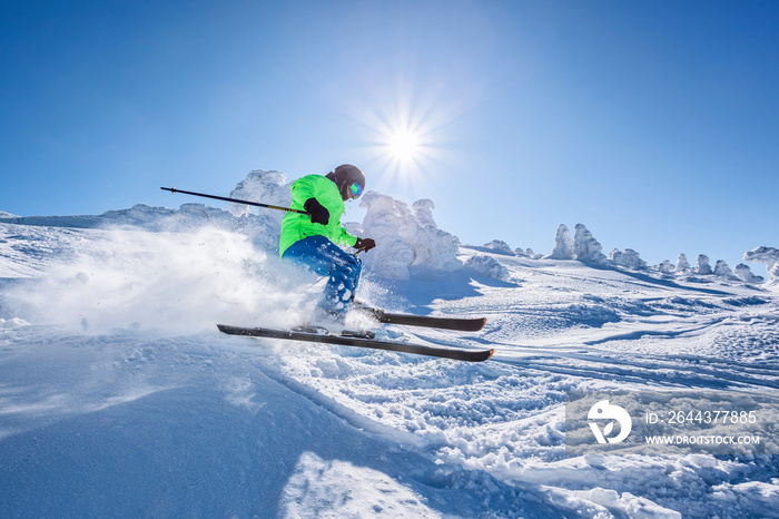 Skier skiing downhill in high mountains against against the fairytale winter forest.