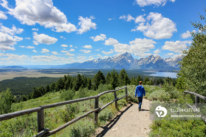 Boy hiking with jackson lake and grand teton mountain in distance