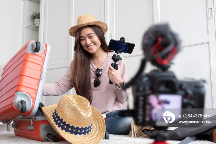 Asian young female blogger recording vlog video with vacation preparing to travel trip at home.online influcencer on social media concept.