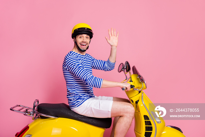 Profile side view of his he nice attractive handsome cheerful cheery glad confident guy driving moped having hi hello good bye isolated over pink pastel color background