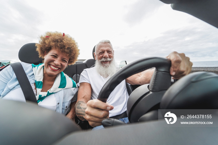 Happy senior couple having fun in convertible car during summer vacation - Focus on hipster man face