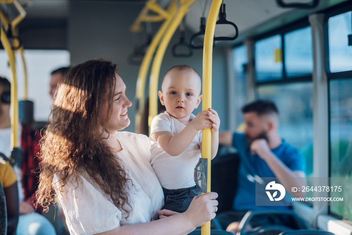 Mother holding her baby boy and riding a bus in the city