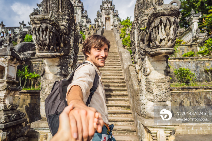 follow me photo. Young man tourist on background of Three stone ladders in beautiful Pura Lempuyang Luhur temple. Summer landscape with stairs to temple. Paduraksa portals marking entrance to middle