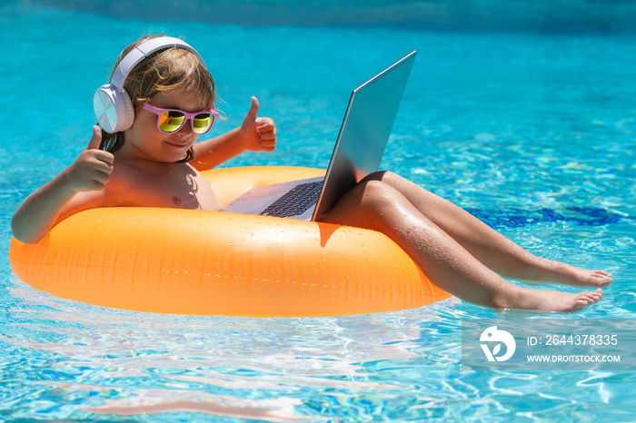 Summer business. Child remote working on laptop in pool. Little business man working online on laptop in summer swimming pool water. Summer office and freelance concept.