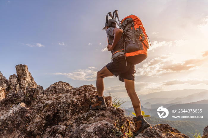 Male hiker with backpack walking on top rock mountain landscape and beautiful view sunset background.Hiker men’s hiking living healthy active lifestyle.