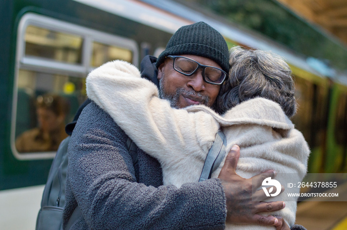 Senior couple embracing at train station