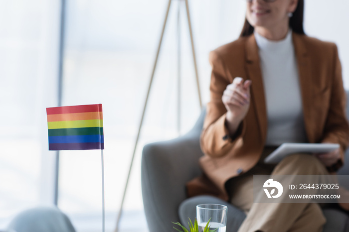 small lgbt flag near cropped psychologist with digital tablet on blurred background