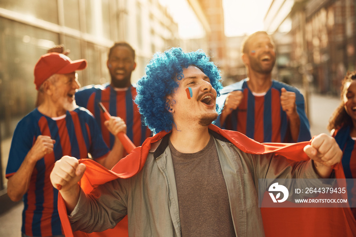 Cheerful sports fan celebrates with his friends on street during soccer word championship.