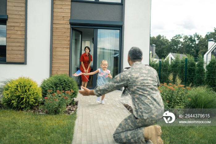 Daughter holding American flag running to father coming back home