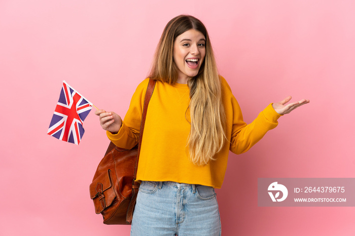 Young blonde woman holding an United Kingdom flag isolated on white background with shocked facial expression