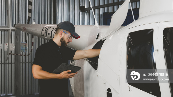 Male mechanic in uniform examining helicopter. Pre flight inspection at the airportы