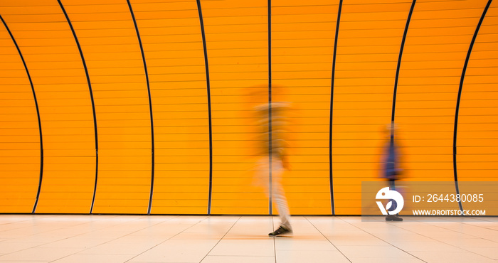 People rushing through a subway corridor (motion blur technique is used to convey movement)