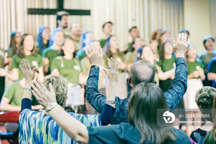 People at church, worshiping God, with hands up.