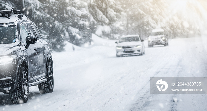 Winter road in beatiful forest. Snow calamity or blizzard. Fast cars on snowy roads in storm.