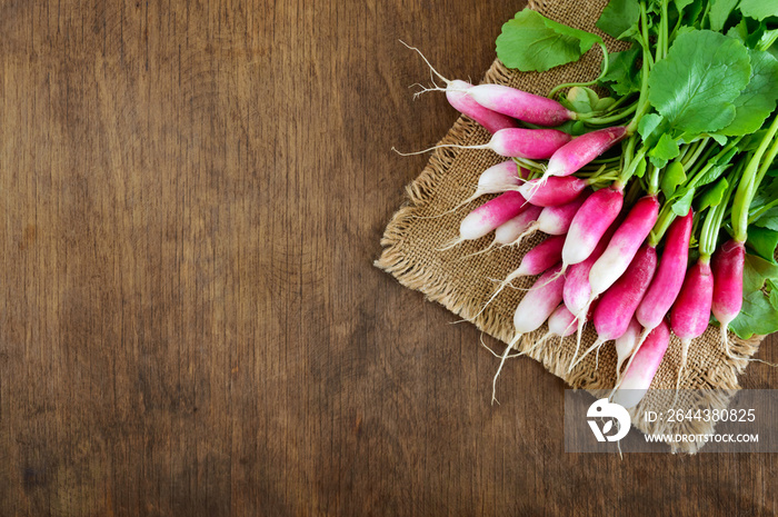 Summer harvested red radish. Growing organic vegetables. Large bunch of raw fresh juicy garden radish on wooden background ready to eat. Closeup.