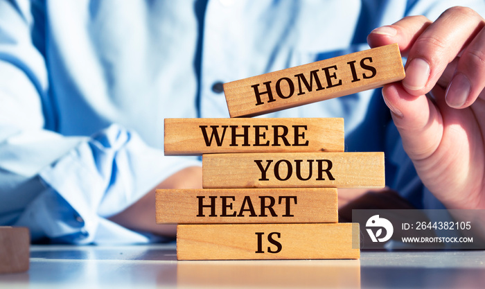 Closeup on businessman holding a wooden block with  Home is Where Your Heart Is  message