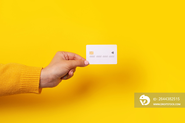 Hand holding blank white credit card mockup, card with electronic chip over yellow background