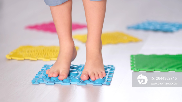 Little boy steps on orthopedic massage mats with different stiffness and texture. Feet Massage Using Trigger Point Spiky Massage Ball. Myofascial Release. close up.