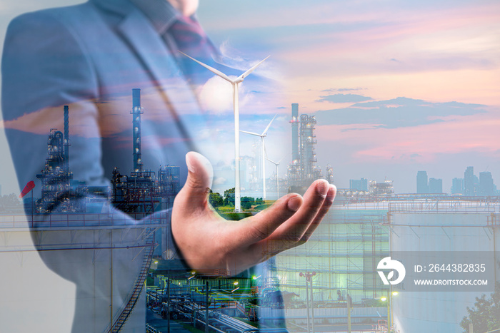 Double exposure of businessman hole wind turbine in hand with oil and gas refinery plant background, alternative energy concept.