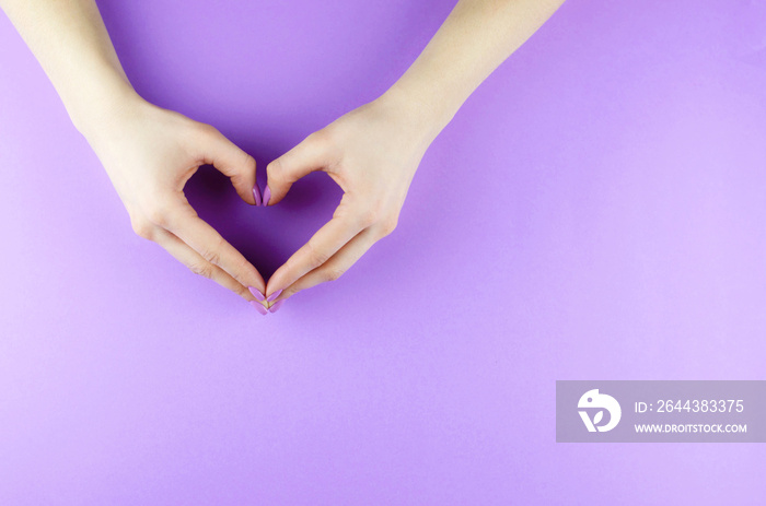 Female hands with a purple manicure in the form of a heart.