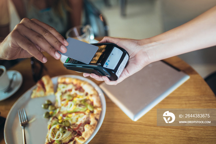 Happy couple using mobile phone and making contactless payment in a restaurant. S