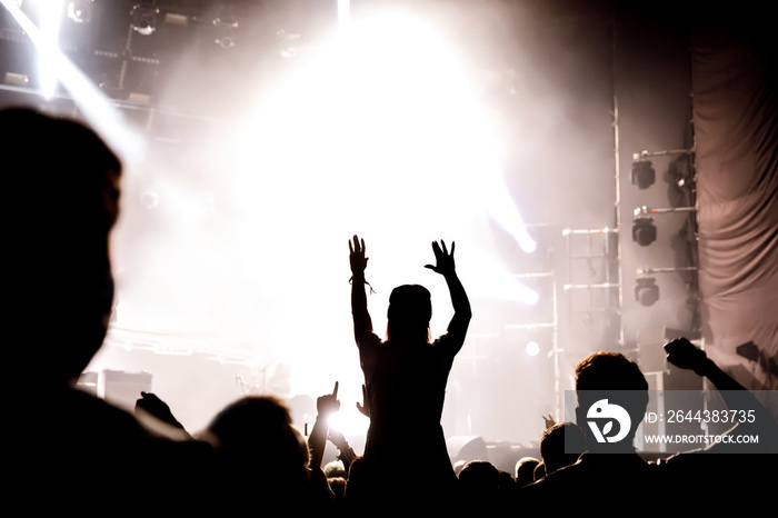 Silhouette of girl with raised hands enjoys the concert