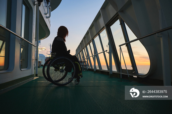 Young woman in wheelchair in sunset on a cruise ship