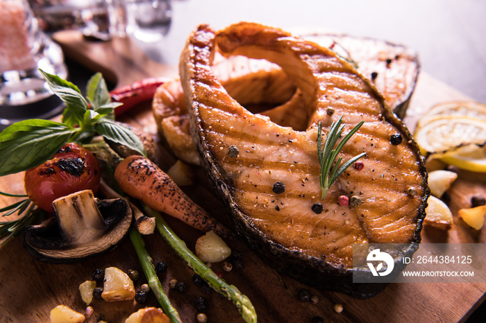 Grilled salmon fish with seasoning and various vegetables on cutting board