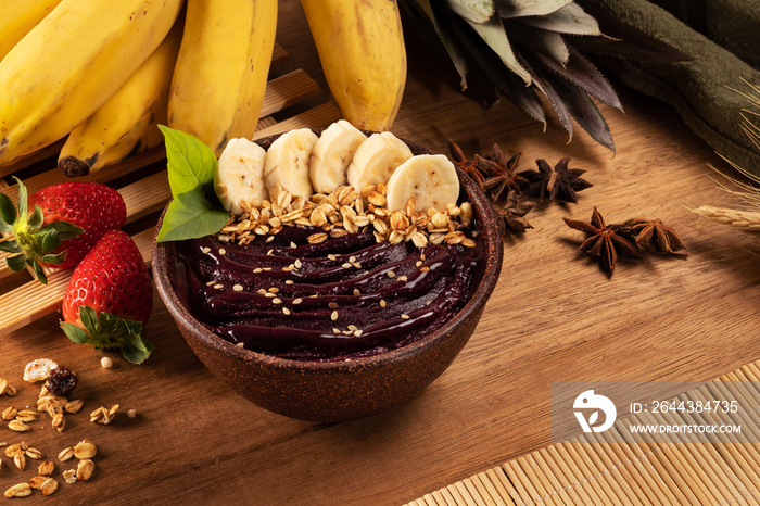 Açaí bowl with fruits and cereal on wooden table