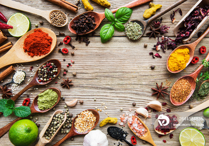 A selection of various colorful spices on a wooden table in  spoons