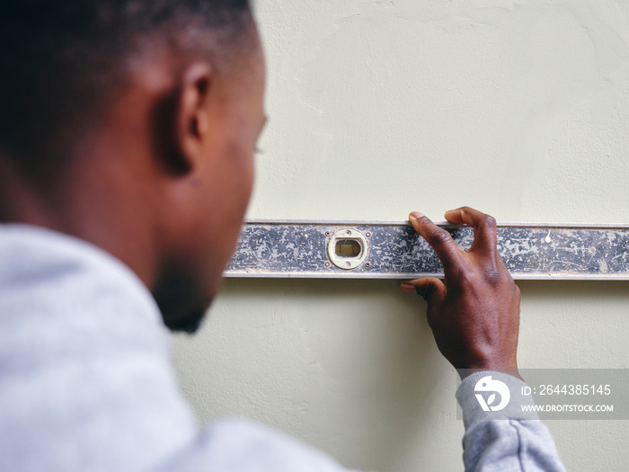 Man using level on house wall