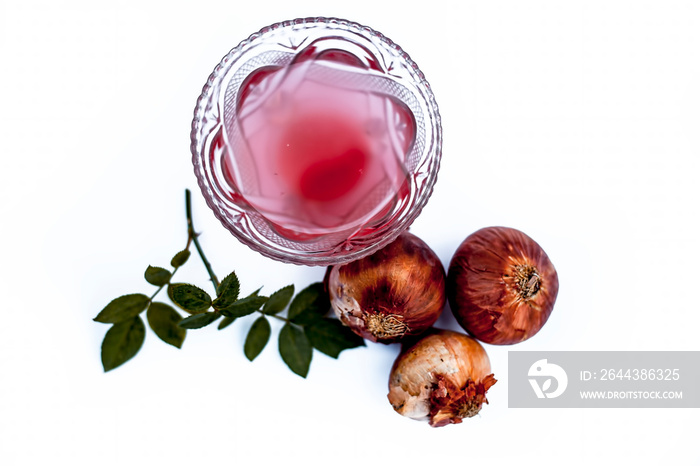 Raw organic fresh onion juice isolated on white with two raw onion  and some rose leaves.