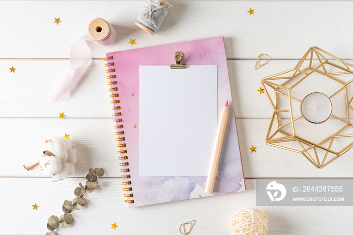 Top view of white working table background with blank paper notebook, nature cotton. Flat lay still life candle, golden paper binder clips. Notepad and pen. Desktop mockup, workspace, stationery.