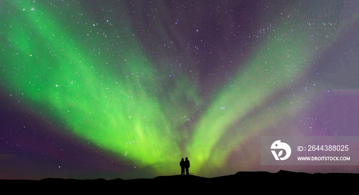 Aurora borealis with silhouette love romantic couple on the mountain.Honeymoon travel concept