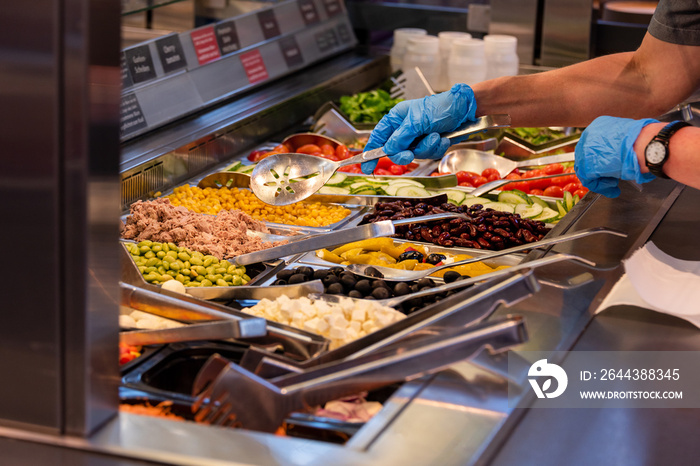 Choosing food from buffet. Fresh salad bar with a variety of fresh vegetables, vegetable table for customers to choose from in a supermarket or restaurant. Buffet in the hotel