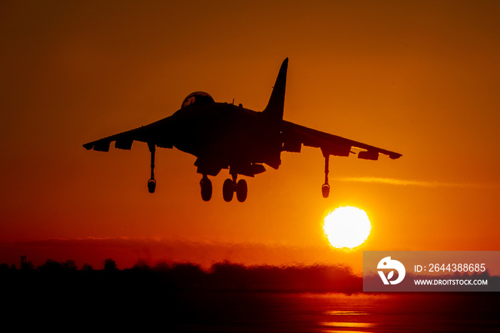 Harrier vertical take off and landing strike fighter landing silhouette at sunset with an orange sky