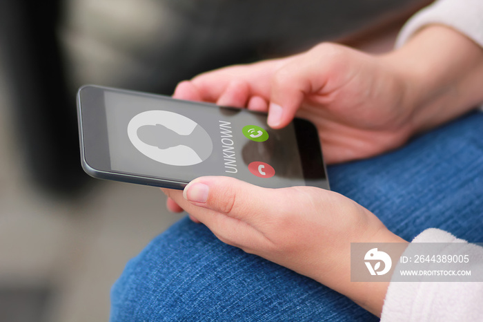 Close up of woman’s hands with smartphone and unknown incoming phone call on it, fraud or scam schemes