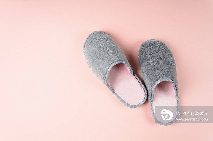 Gray and pink home slippers on a pastel paper background. Top view. Copy space