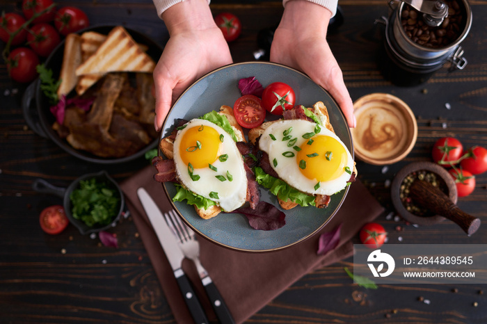 Tasty breakfast - fried egg toasts, bacon, tomatoes on wooden kitchen table