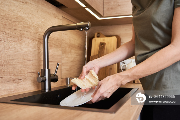 Woman wash dishes with organic eco friendly sponge. Zero waste concept