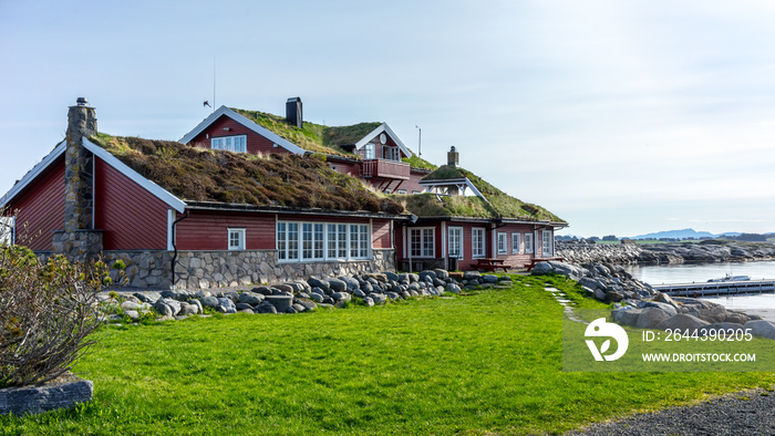 Red wooden house with grass roof in the seaside in Hustadvika near the Atlantic Road, Norway