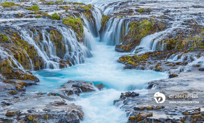 Incredible view of Bruarfoss Waterfall. The ’Iceland’s Bluest Waterfall.’ Blue water flows over stones. Midnight sun of Iceland. Visit Iceland. Beauty world.