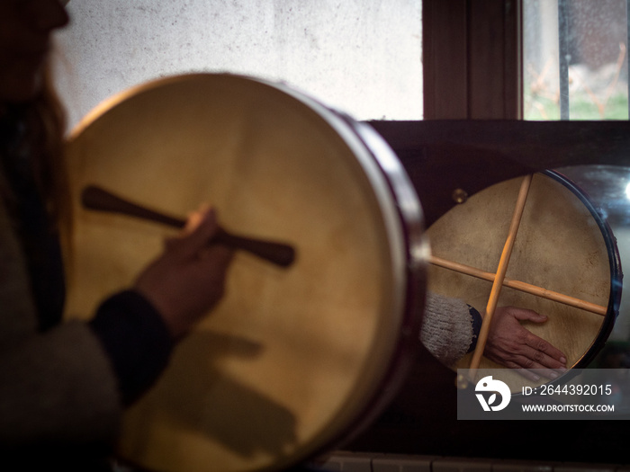 Close up of female playing a bodhran drum and reflection in the mirror.