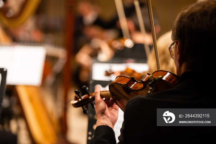 Symphony orchestra on stage, hands playing violin