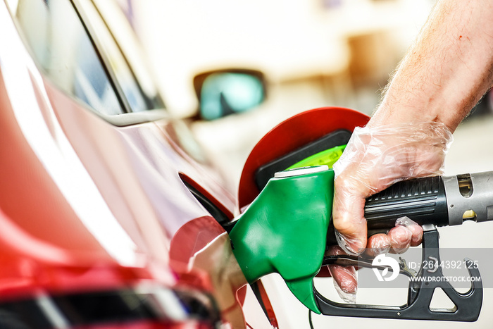 Man at gas Station refueling gasoline or diesel. Hand with clear gloves holding fuel pump or pistol.