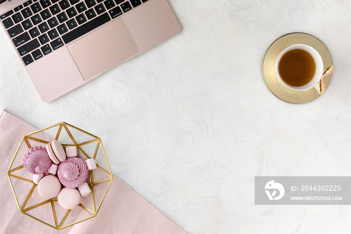 Stylish women’s office desk, flat lay. Feminine workspace with, laptop, cup of herbal tea and dessert. Female table on white background. Flatlay, top view