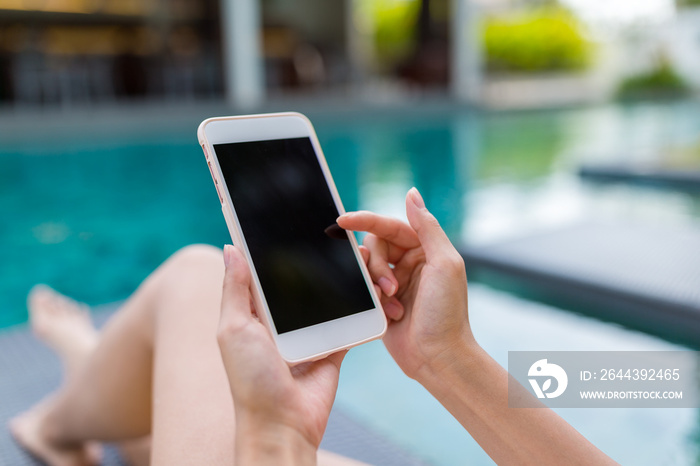 Woman using her mobile phone and relaxing on swimming pool