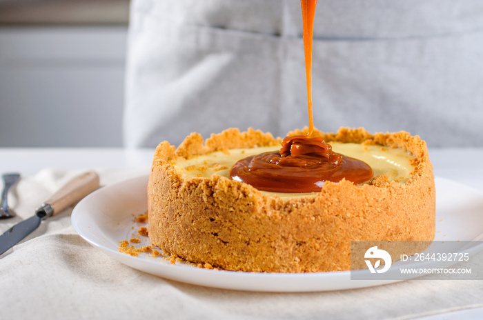 Close up of confectioner decorating orange cheesecake with caramel