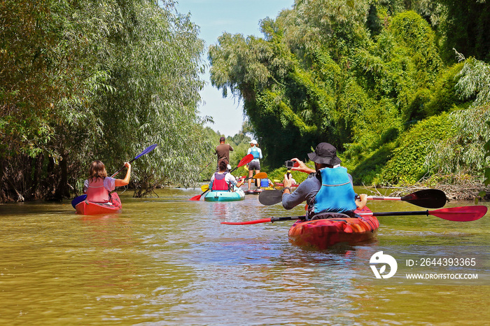 Kayaking in wilderness of Danube river and biosphere reserve in summer. Peacefull nature scene of calm river. Water tourism concept. Group of friends (people) travel by kayaks.